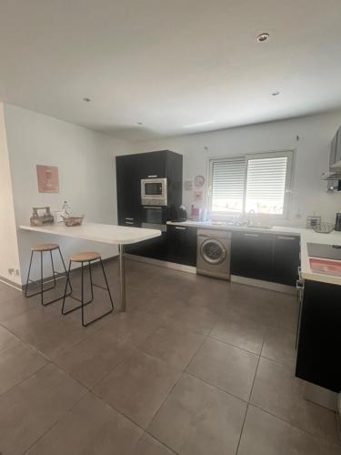 - une cuisine avec une table et deux tabourets dans l'établissement Charmant T2 en bas de villa avec jardin, à Ajaccio