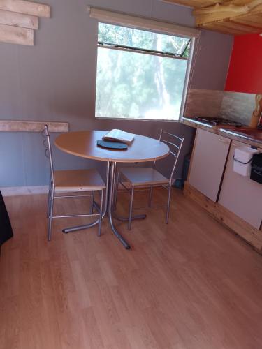 - une table et des chaises dans une petite chambre avec fenêtre dans l'établissement Séjour à la ferme, à Valuéjols