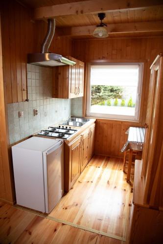 a kitchen with a stove and a white refrigerator at Domki Letniskowe Bursztynek in Grzybowo