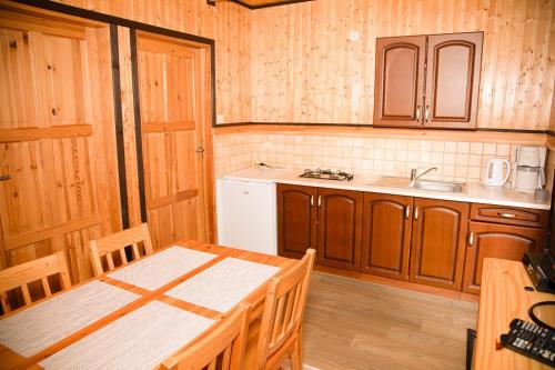 a kitchen with wooden cabinets and a table and a sink at Domki Letniskowe Bursztynek in Grzybowo