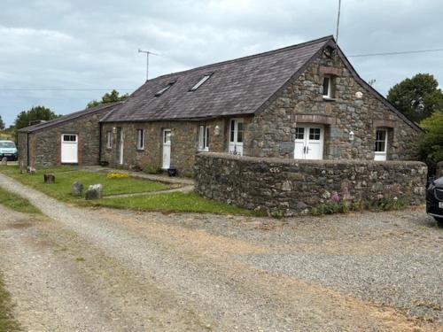 a stone house on the side of a dirt road at Holmws Holiday Cottages in Newport