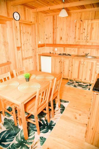a dining room with a wooden table and chairs at Domki Letniskowe Bursztynek in Grzybowo