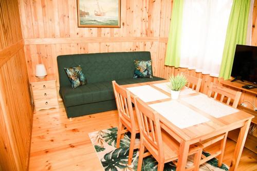a living room with a table and a green couch at Domki Letniskowe Bursztynek in Grzybowo