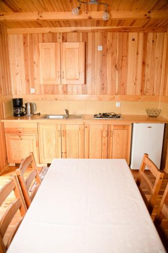 a kitchen with a white table and wooden cabinets at Domki Letniskowe Bursztynek in Grzybowo