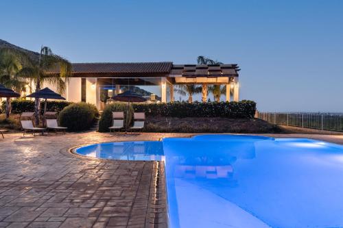 a swimming pool in front of a house at Agriturismo Alle Riserve Cavagrande in Avola