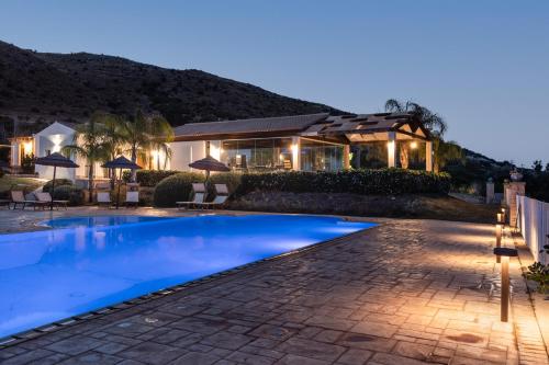 a swimming pool in front of a house at night at Agriturismo Alle Riserve Cavagrande in Avola