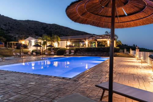 an umbrella sitting next to a swimming pool at Agriturismo Alle Riserve Cavagrande in Avola