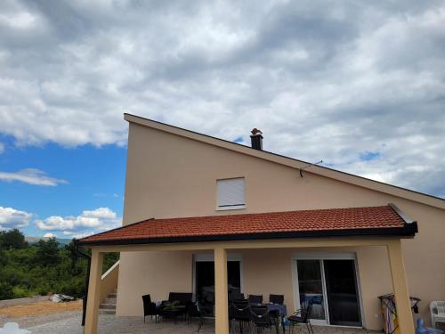 a house with chairs and a roof with a sky at Stan na dan BOVKA in Široki Brijeg