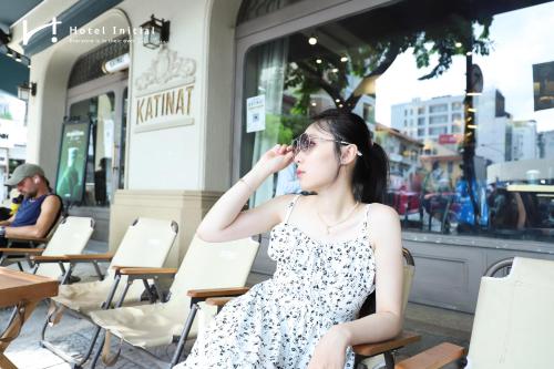 a woman sitting in a chair outside a restaurant at Hotel Initial-Benthanh in Ho Chi Minh City