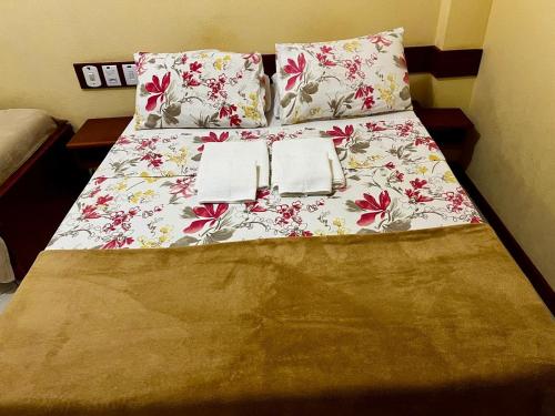 a bed with two pillows and a floral bedspread at Pousada Maravista in Anchieta