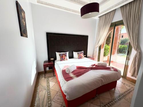 a bedroom with a bed and a large window at Appartement standing piscine la palmeraie in Marrakech