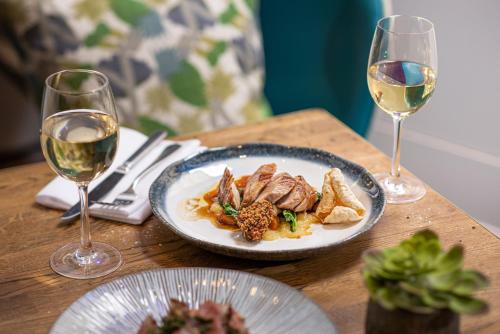 a table with a plate of food and two glasses of wine at Harbour Hotel & Spa Bristol in Bristol
