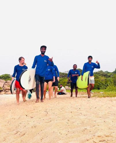 a group of men walking on the beach with surfboards at Star Rest Beach Hotel in Arugam Bay