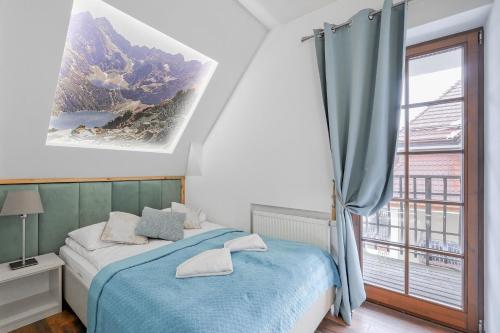a bedroom with a blue bed and a window at Rezydencja Sienkiewicza in Zakopane