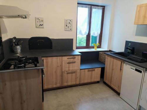 a kitchen with wooden cabinets and a stove and a window at Gite du Pré Bouquin in Ménil-de-Senones