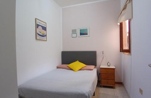 a white bedroom with a bed and a yellow pillow at La Casita de Puerto in Puerto del Rosario