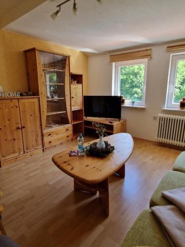 a living room with a coffee table and a tv at Pension Haus Sonneck in Wildemann