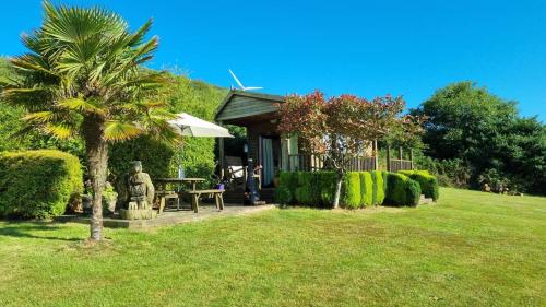 a house with a palm tree in a yard at The Cabin in St Austell