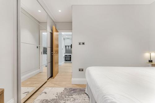 a bedroom with a white bed and a hallway at LuxLet Apartments - Heart of Hampstead, London in London