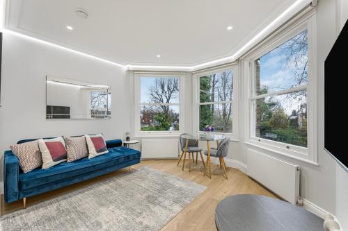 a living room with a blue couch and windows at LuxLet Apartments - Heart of Hampstead, London in London