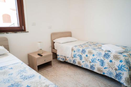 a bedroom with two beds and a table with a lamp at Hotel Indaco in Marina di Casalvelino