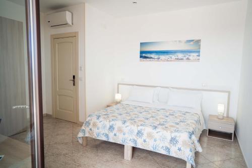 a white bedroom with a bed and a picture on the wall at Hotel Indaco in Marina di Casalvelino