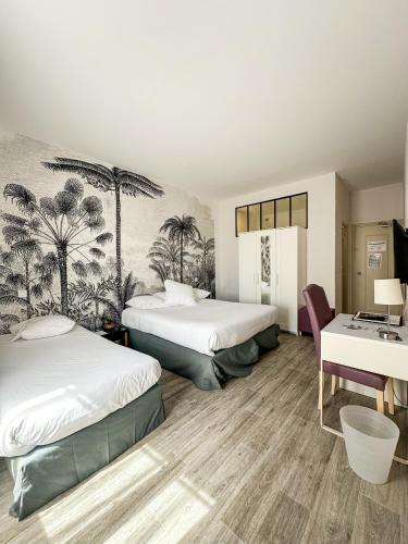 a hotel room with two beds and a desk at Hotel Les Palmiers in Sainte-Maxime