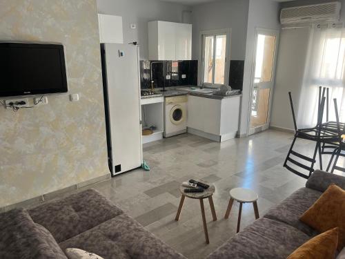 a living room with a couch and a kitchen at Appartement meublé haut standing 2 chambres 200m de la mer in Soliman