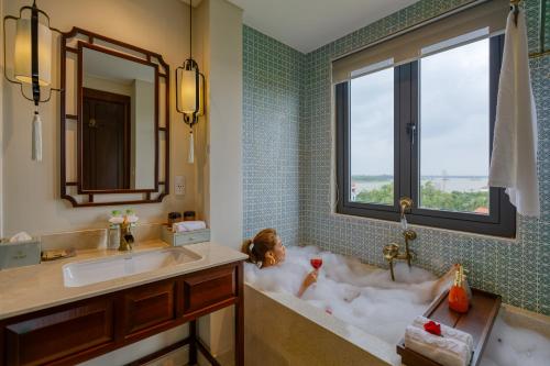 a bathroom with a dog laying in a bath tub at Cozy Savvy Hoi An - The Quintessence of Exquisite Retreat in Hoi An