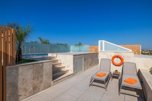 a patio with two chairs and a bar on a wall at Salmar Court Holiday Apartments with Pool in Hal Ghaxiak