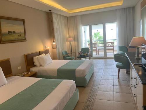 a hotel room with two beds and a balcony at Lahami Bay Beach Resort in Abū Ghuşūn