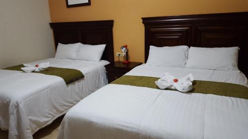 Dos camas en una habitación de hotel con animales de peluche. en Apart Hotel Pico Bonito, en La Ceiba