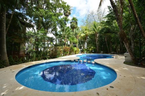 una gran piscina azul con árboles en el fondo en Spacious and luxurious villa with 4 bedrooms, swimming pool, tennis court, and beach within walking distance, en Playa del Carmen