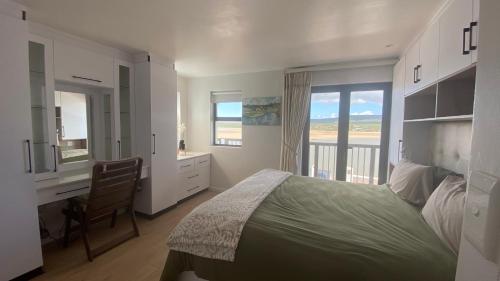 a bedroom with a bed and a desk and a window at Witsand Holiday House in Witsand