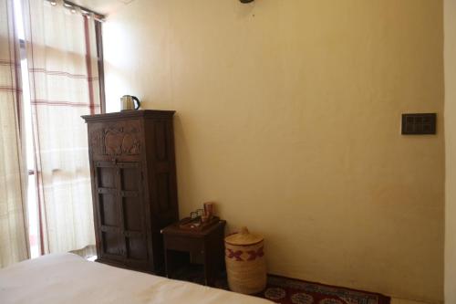 a bedroom with a bed and a dresser and a window at Vedic Dham Ganga in Rishīkesh