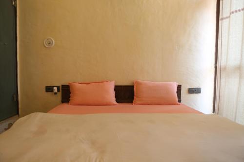 a bed with two orange pillows in a room at Vedic Dham Ganga in Rishīkesh