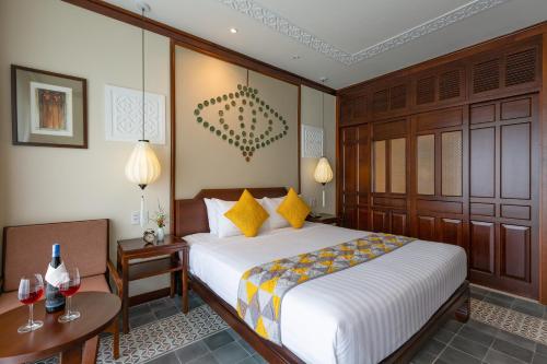 a bedroom with a bed and two tables with wine glasses at Cozy Savvy Hoi An - The Quintessence of Exquisite Retreat in Hoi An