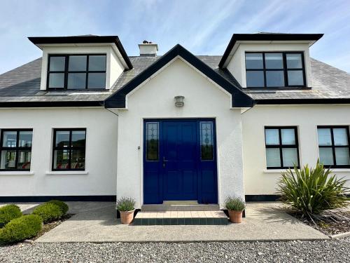 a white house with a blue door at Grianán in Ballyconneely