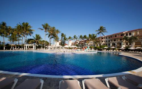 a large swimming pool with chairs and palm trees at Samba Vallarta All Inclusive in Nuevo Vallarta 