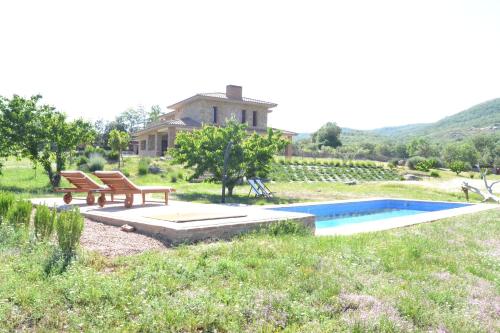 a swimming pool with two benches and a house at Agua Antigua Casa Rural in Gargüera