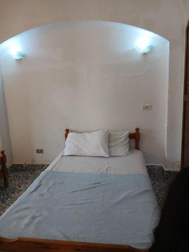a bed in a room with a white wall at Ma Sou in El Alamein