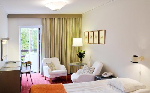a hotel room with a bed and chairs at Ariston Hotell in Lidingö