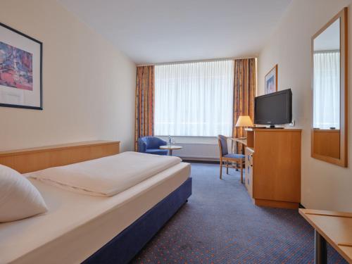 a hotel room with a bed and a flat screen tv at YORS Hotel Hannover in Hannover