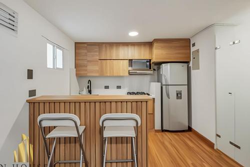 a kitchen with a counter with stools and a refrigerator at Aria Living 201 - Where Design and Location Shine in Guayaquil