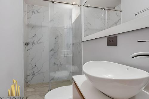 a white bathroom with a sink and a shower at Aria Living 300 - Style and Urban Comfort in Guayaquil