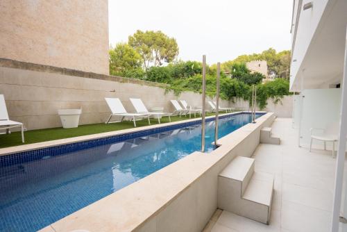 an outdoor swimming pool with white lounge chairs next to a building at Hotel Morlans Suites - Adults Only in Paguera
