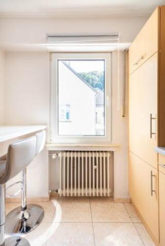 a kitchen with a window and a chair and a radiator at Centerluxfirst in Ferme Thibesart