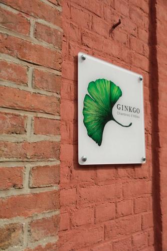 a sign with a green leaf on a brick wall at Ginkgo Maison d'hôtes in Amiens