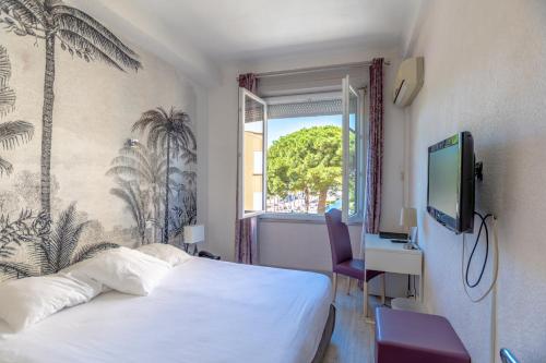 a hotel room with a bed and a window at Hotel Les Palmiers in Sainte-Maxime
