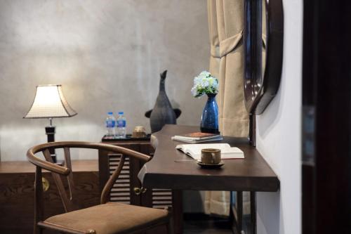 a table with a chair and a vase with flowers at Cozy Savvy Hoi An - The Quintessence of Exquisite Retreat in Hoi An